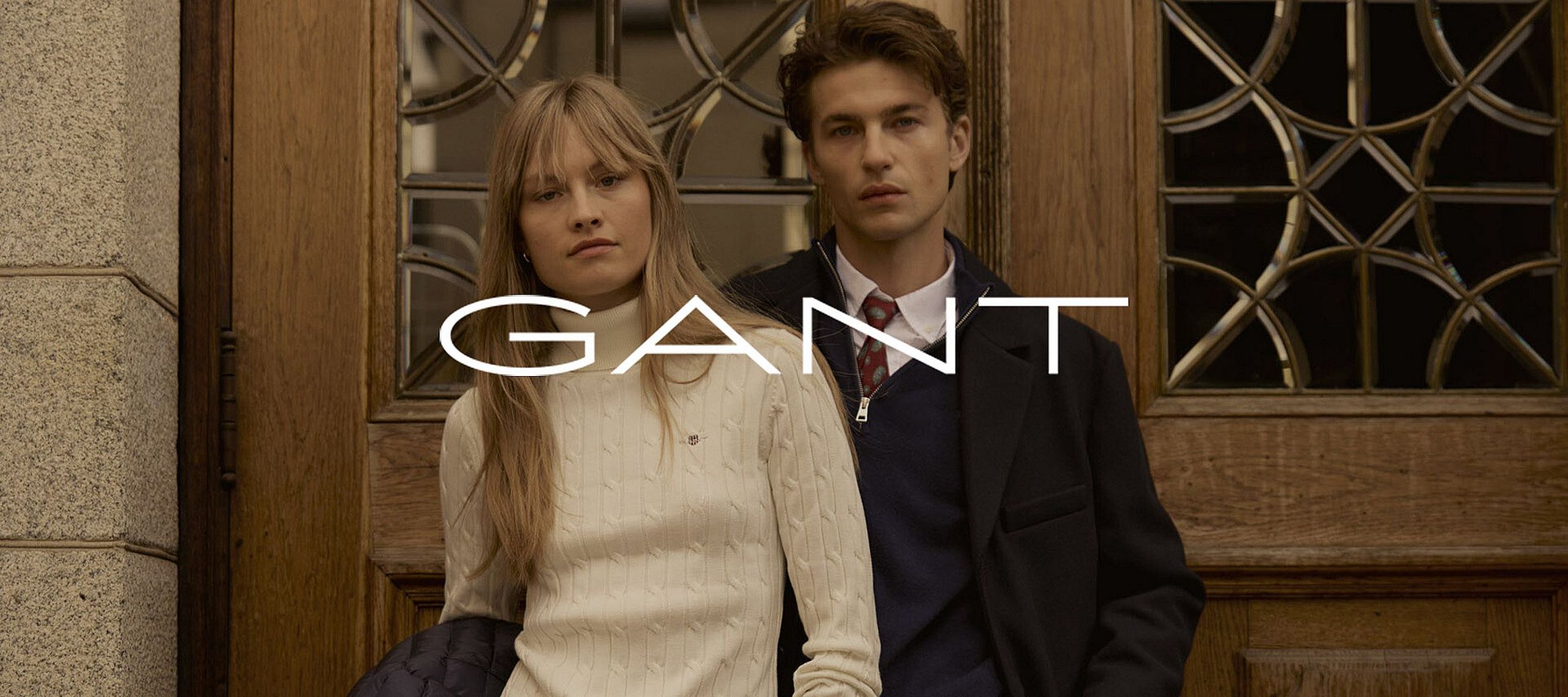 Un uomo e una donna in piedi davanti a una porta, vestiti con abiti Gant