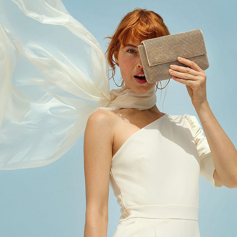 Una donna tiene una piccola borsetta sul viso, coprendo un occhio.