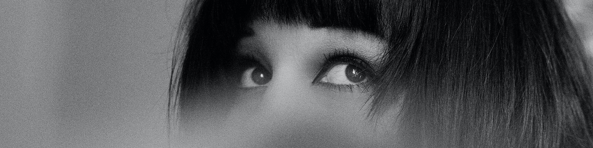 Viene mostrata la parte superiore del viso di una donna. Si vedono solo la frangia sulla fronte e gli occhi. L'immagine funge da intestazione per la pagina delle notizie.